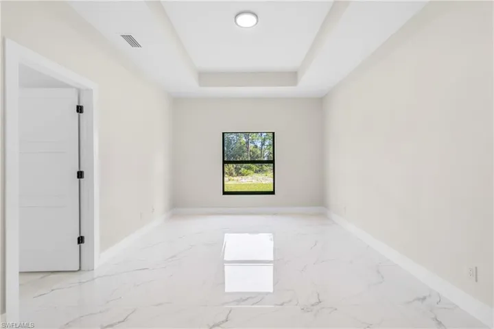 Empty room featuring light marble finish floors and a raised ceiling
