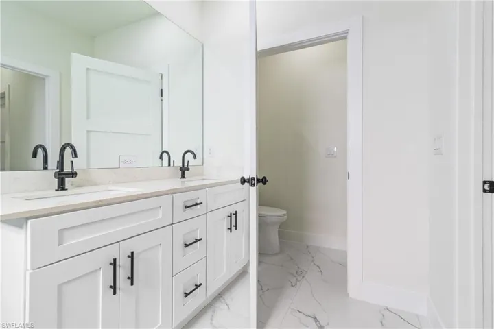 Full bathroom with double vanity and light marble finish floors