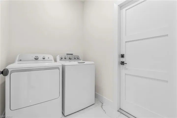 Laundry room with light marble finish flooring and washer and clothes dryer