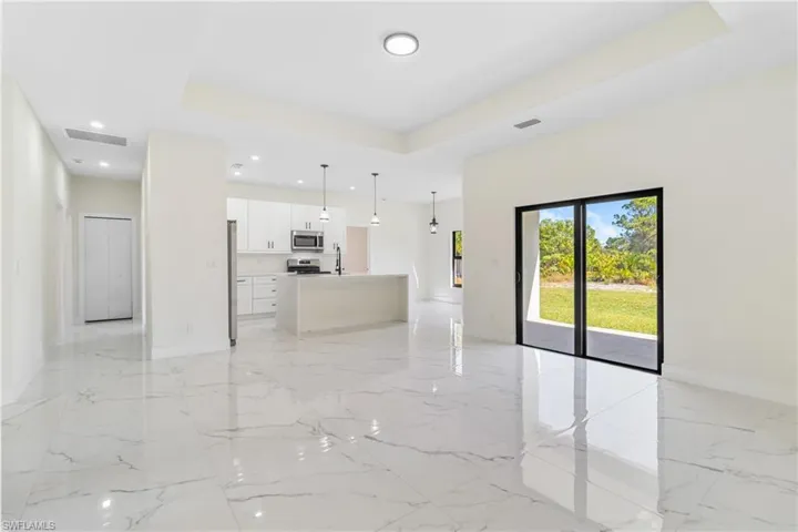 Unfurnished living room featuring light marble finish flooring, a tray ceiling, and recessed lighting