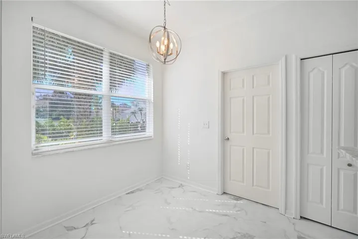 Unfurnished dining area featuring suspended lighting and marble look tile flooring
