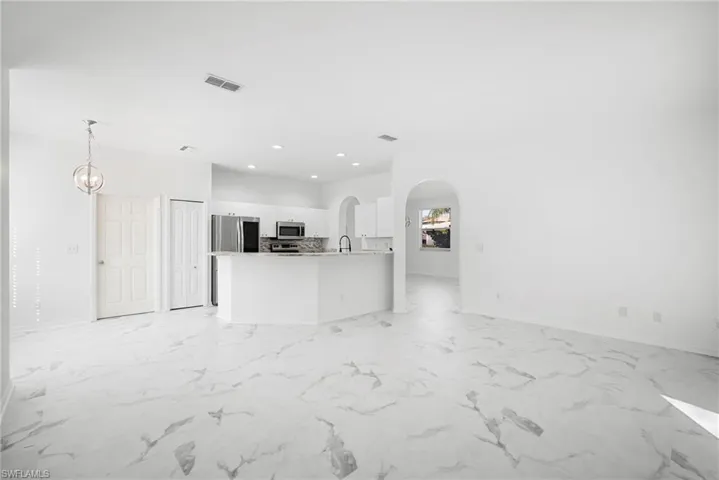 Unfurnished living room with recessed lighting, arched walkways, and light marble finish floors