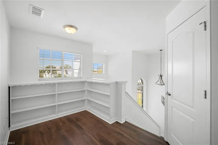 Corridor featuring an upstairs landing and dark wood finished floors