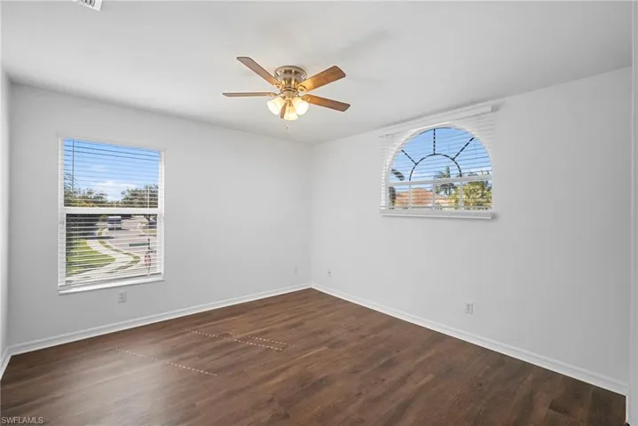 Unfurnished room with dark wood finished floors and a ceiling fan