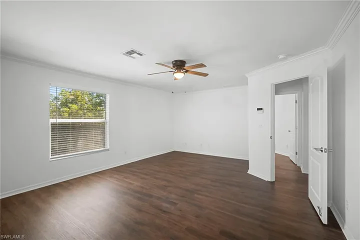 Spare room with ornamental molding, a ceiling fan, and dark wood-type flooring