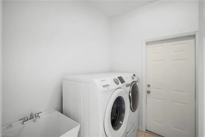 Laundry area with washing machine and dryer and light tile patterned flooring