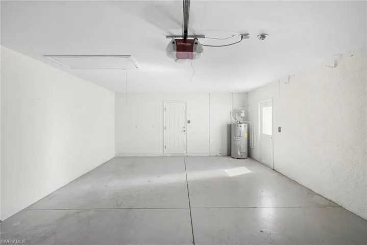 Garage with electric water heater, a garage door opener, and a textured wall