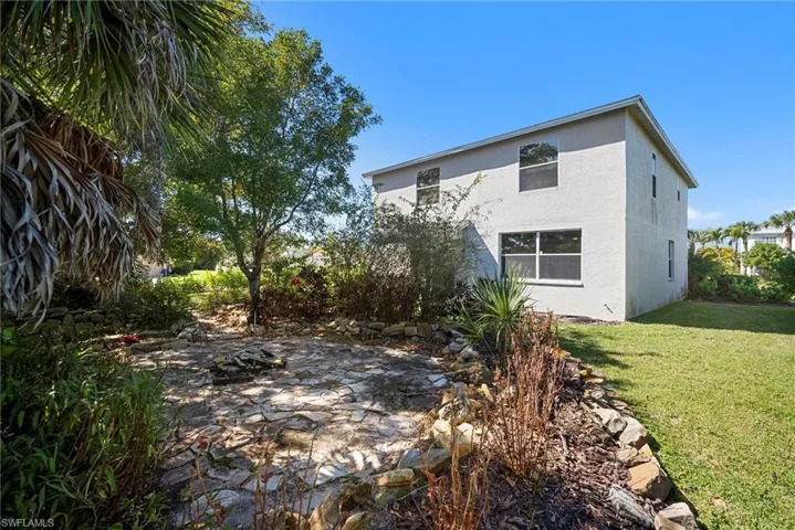 Rear view of property featuring a lawn and stucco siding
