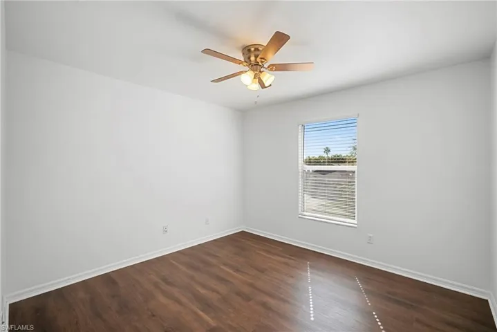 Unfurnished room with dark wood finished floors and a ceiling fan