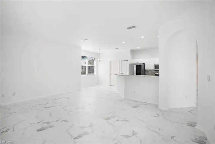 Unfurnished living room with light marble finish flooring and a chandelier