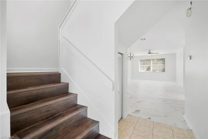 Stairs with tile patterned flooring and a ceiling fan