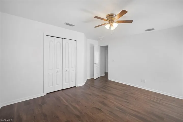 Unfurnished bedroom featuring ceiling fan, dark wood-style floors, and a closet