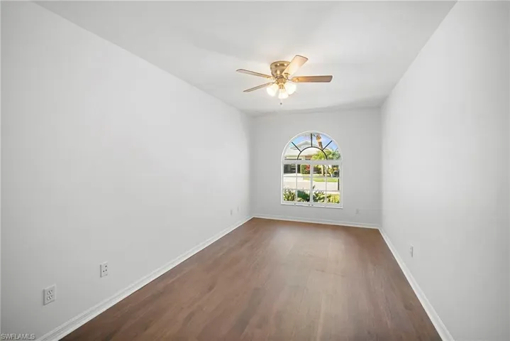 Unfurnished room featuring a ceiling fan and dark wood-style floors