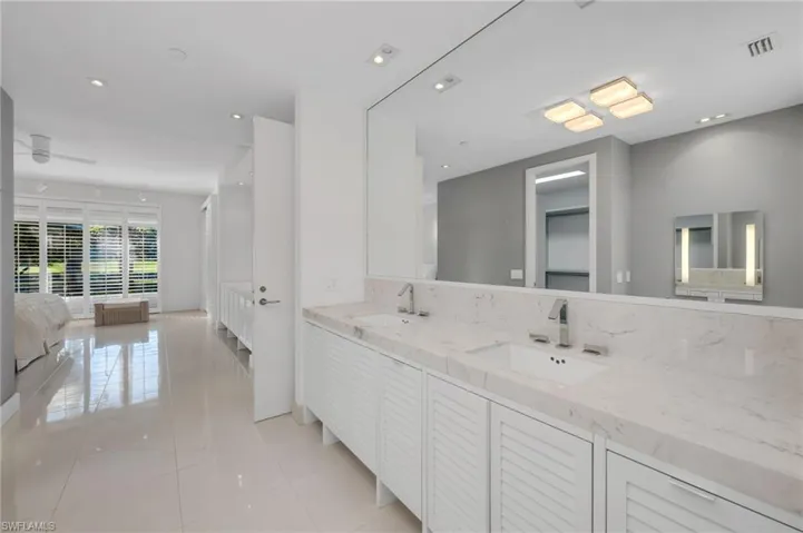 Seamless flow from Primary Bedroom to Bathroom.  A matching vanity can be seen in large profile mirror.