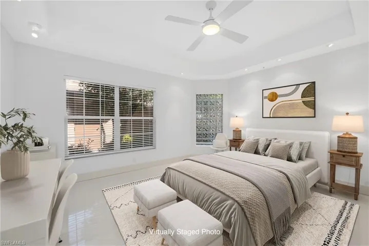 Virtually staged bed, rug, art, ottomans, plant.