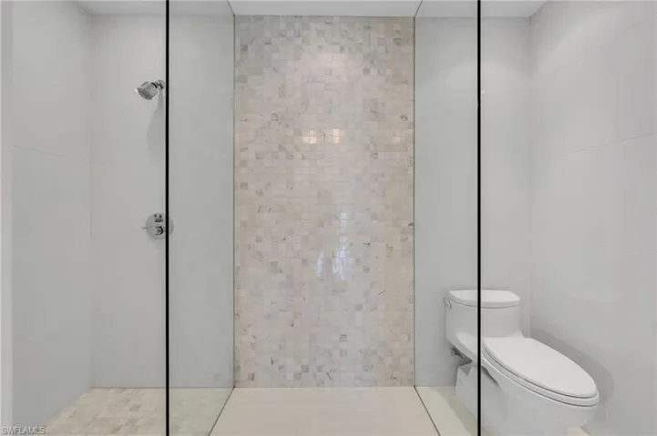 Marble feature wall with shower and seamless glass enclosure.
