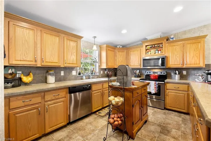Kitchen with appliances with stainless steel finishes, light tile patterned floors, and backsplash