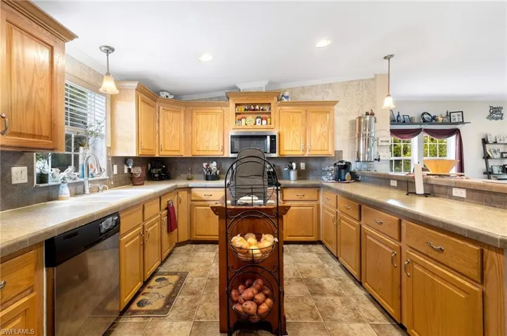 Kitchen featuring ornamental molding, appliances with stainless steel finishes, a healthy amount of sunlight, and light tile patterned floors