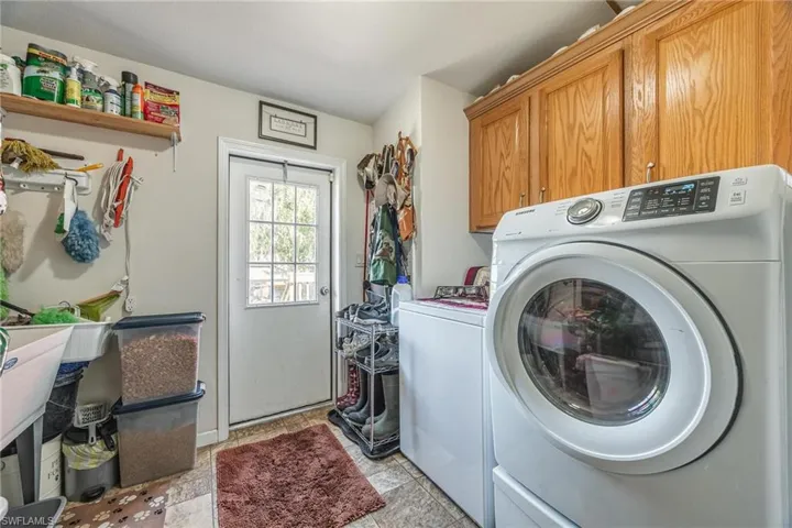 Washroom with cabinets, washer and dryer, and light tile patterned floors