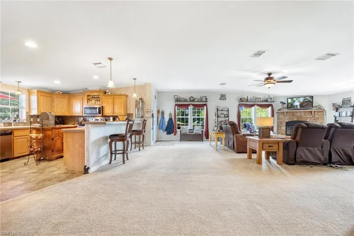 Carpeted living room with a healthy amount of sunlight and ceiling fan