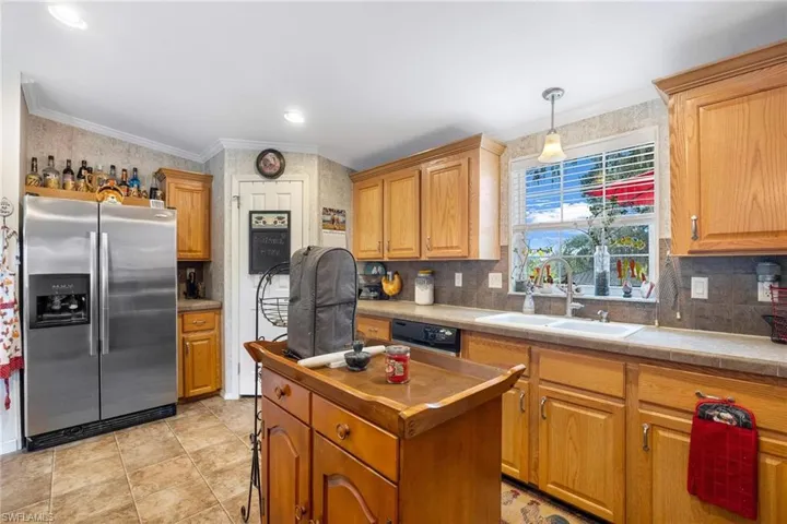 Kitchen with dishwashing machine, tasteful backsplash, stainless steel refrigerator with ice dispenser, pendant lighting, and sink