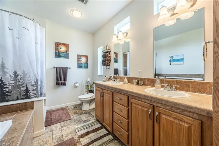 Bathroom with tile patterned flooring, dual vanity, and toilet