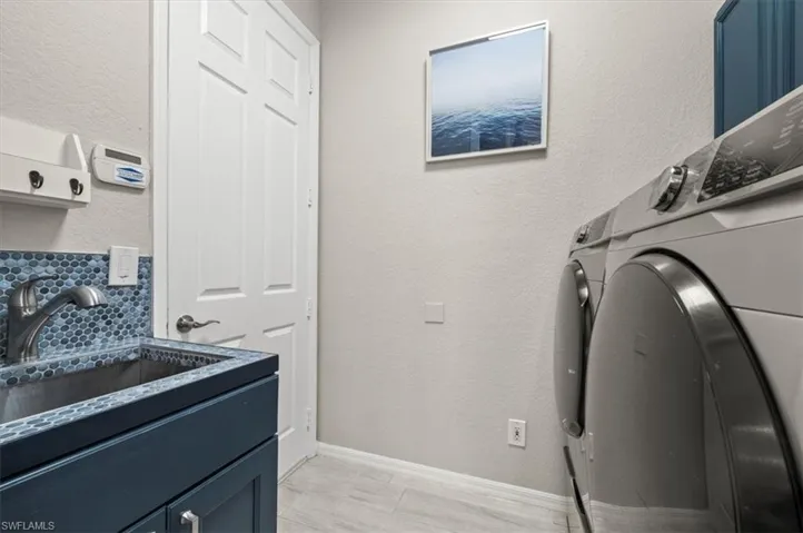 Clothes washing area with cabinets, sink, and separate washer and dryer