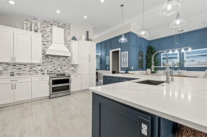 Kitchen featuring pendant lighting, stainless steel electric range, white cabinetry, and custom exhaust hood