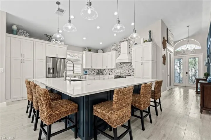Kitchen featuring plenty of natural light, sink, french doors, and a large island with sink