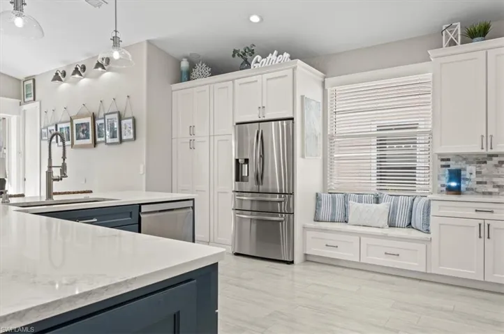 Kitchen featuring white cabinetry, sink, appliances with stainless steel finishes, backsplash, and pendant lighting