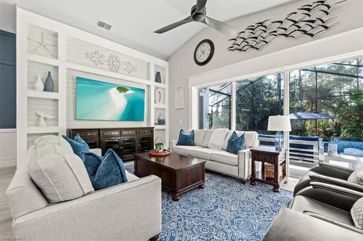 Living room with a wealth of natural light, ceiling fan, light hardwood / wood-style floors, and vaulted ceiling