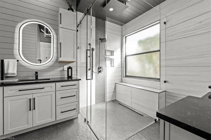 Bathroom featuring wood walls, a shower with shower door, and vanity