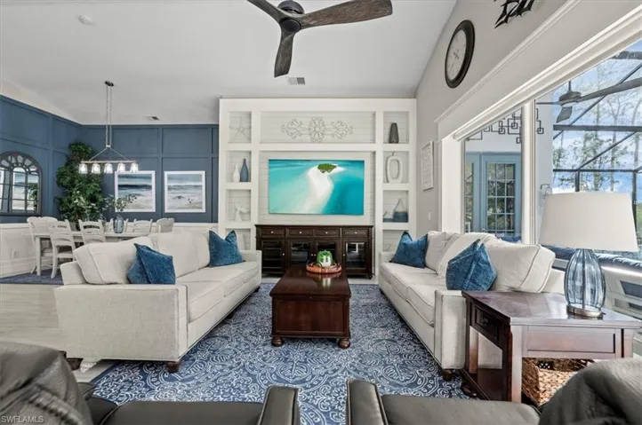 Living room featuring built in shelves and ceiling fan with notable chandelier