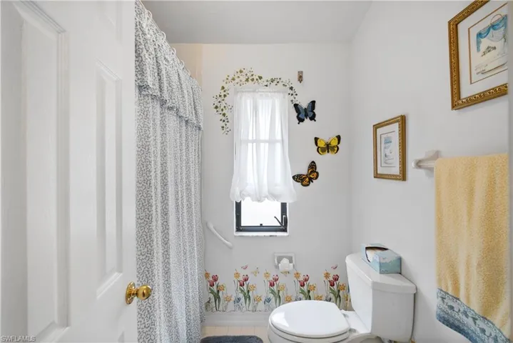 Bathroom with toilet, tile patterned floors, and plenty of natural light