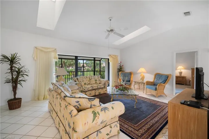 Living room with vaulted ceiling, light tile patterned floors, and ceiling fan