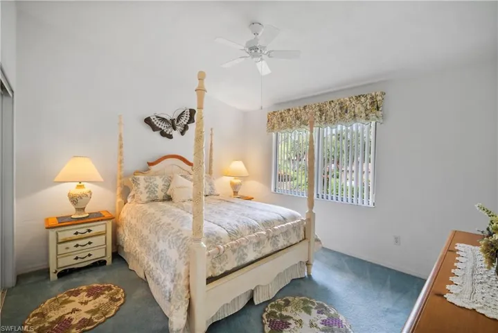 Bedroom with ceiling fan and dark colored carpet