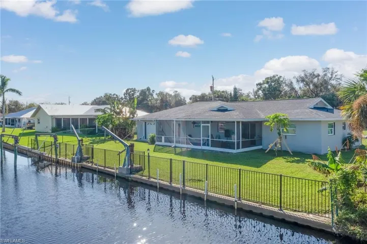 Back of property with a sunroom, a lawn, and a water view