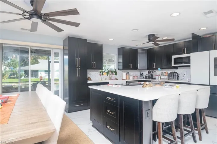 Kitchen with tasteful backsplash, a kitchen bar, a center island, ceiling fan, and white refrigerator