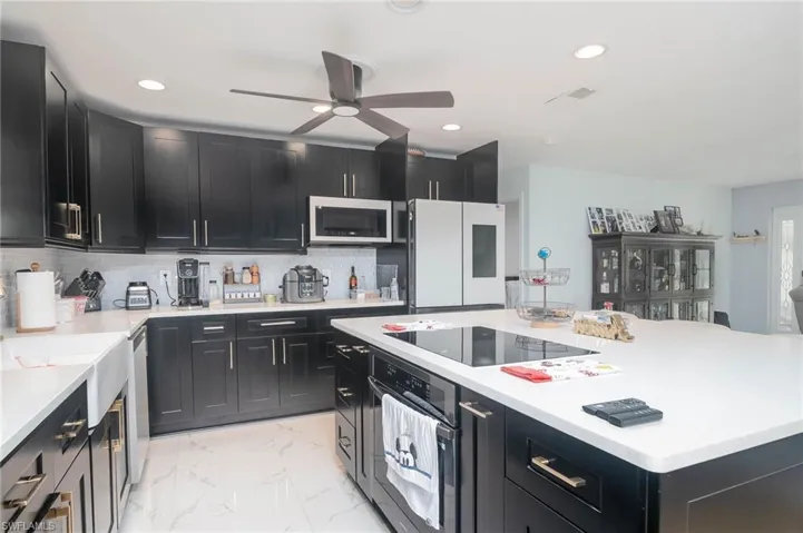 Kitchen with backsplash, appliances with stainless steel finishes, a center island, and ceiling fan