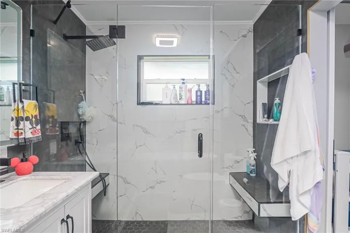 Bathroom featuring vanity, crown molding, and walk in shower