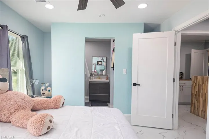 Bedroom featuring connected bathroom, ceiling fan, and multiple windows