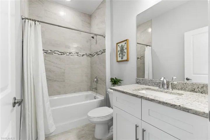 Full bathroom featuring vanity, toilet, tile patterned floors, and shower / bath combination with curtain