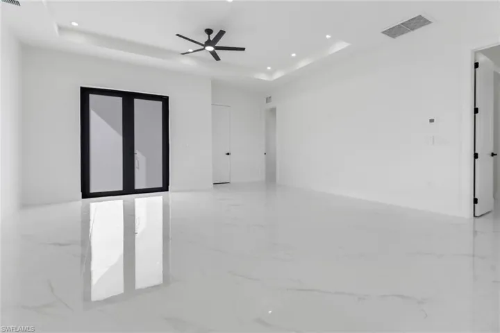 Empty room with ceiling fan and a raised ceiling