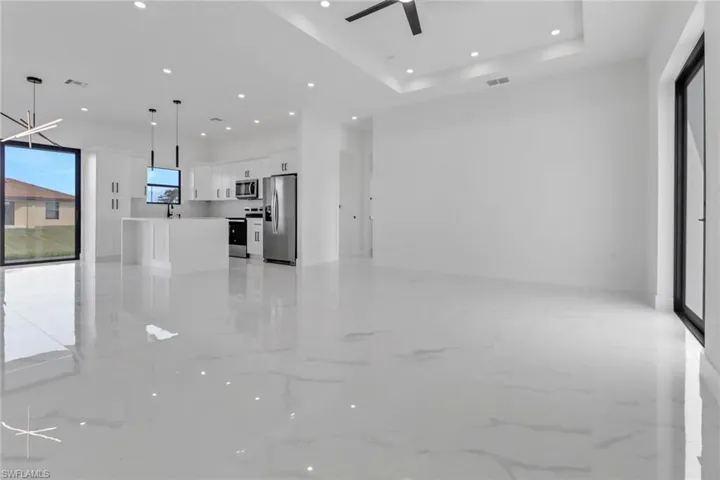 Unfurnished living room with ceiling fan and a raised ceiling