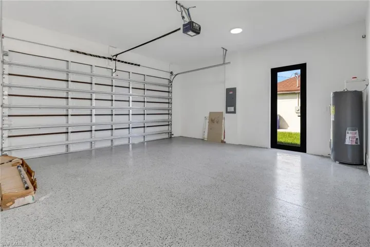 Garage with water heater, electric panel, and a garage door opener