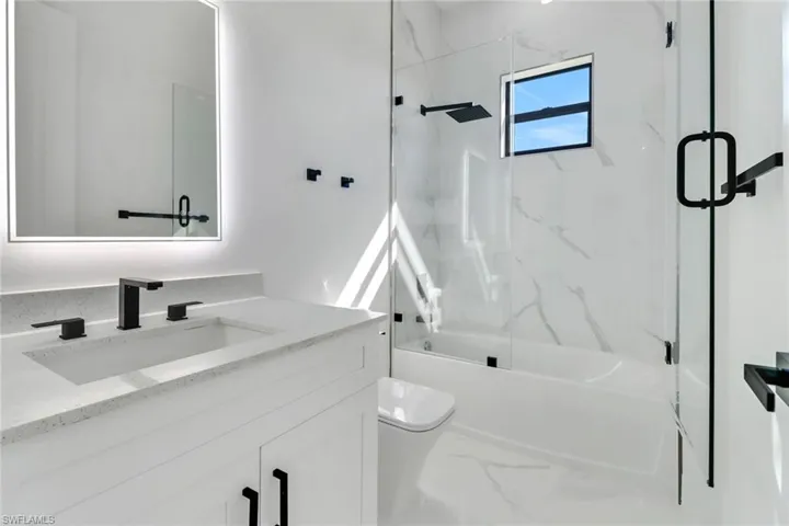 Full bathroom featuring vanity, shower / bath combination with glass door, and toilet