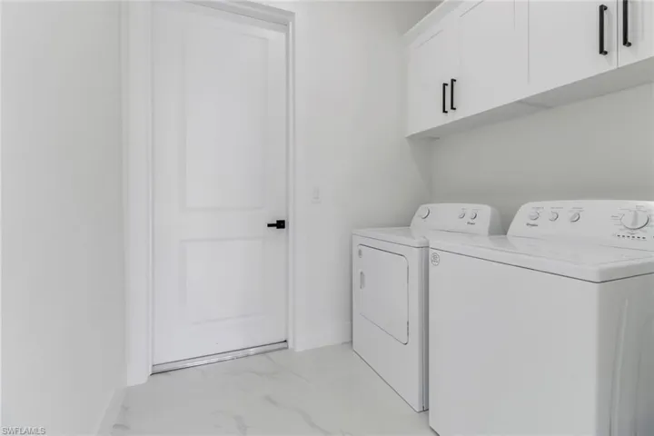 Washroom with cabinets and washer and clothes dryer