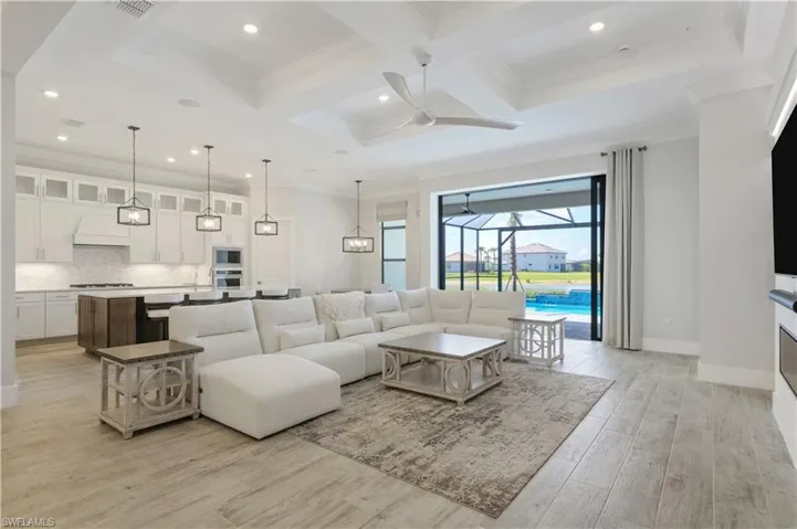 Living area featuring a ceiling fan, coffered ceiling, crown molding, beamed ceiling, and light wood-style floors