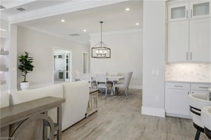 Living room with a chandelier, crown molding, light wood-style floors, and recessed lighting