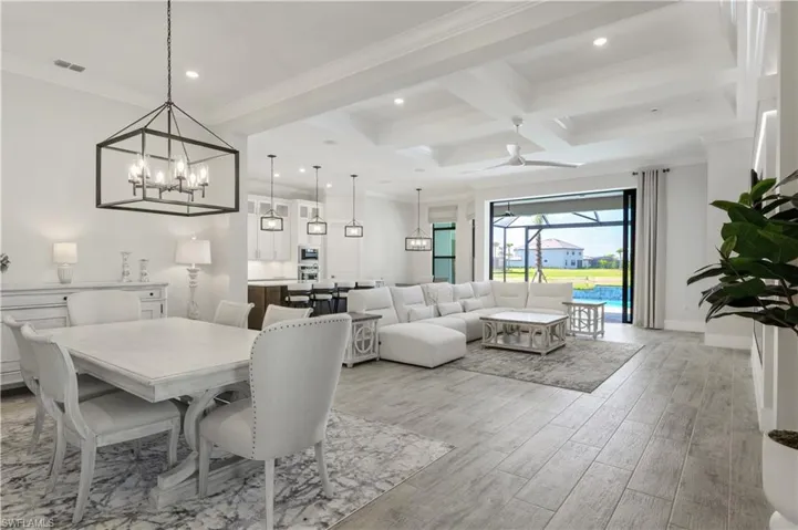 Dining area featuring ceiling fan, light wood-style floors, coffered ceiling, ornamental molding, and beamed ceiling